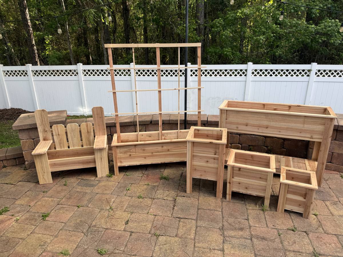 Full collection of handcrafted cedar planters on a brick patio in St. Johns FL — bench planter, long box, and trio set