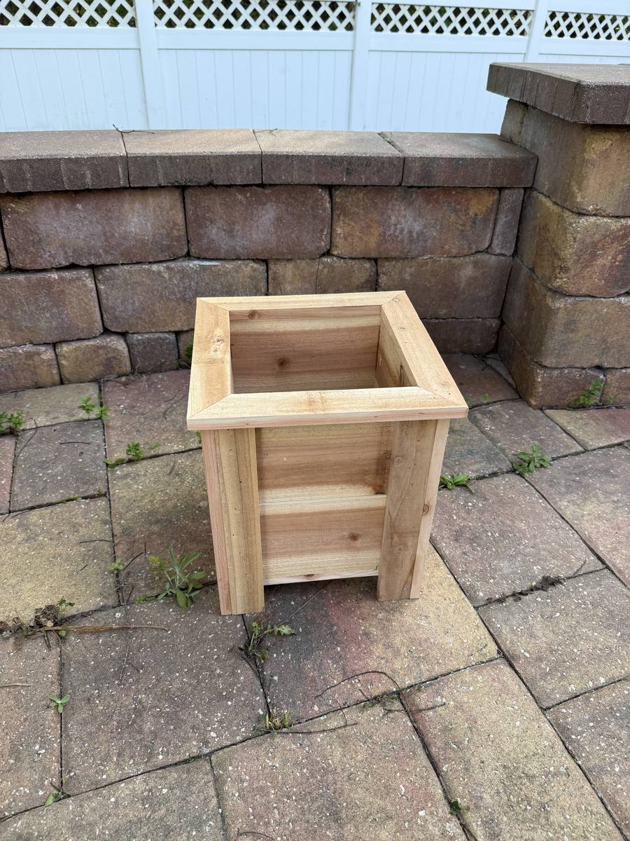 Medium cedar square planter box with mitered top frame on brick patio — approximately 14x14 inches