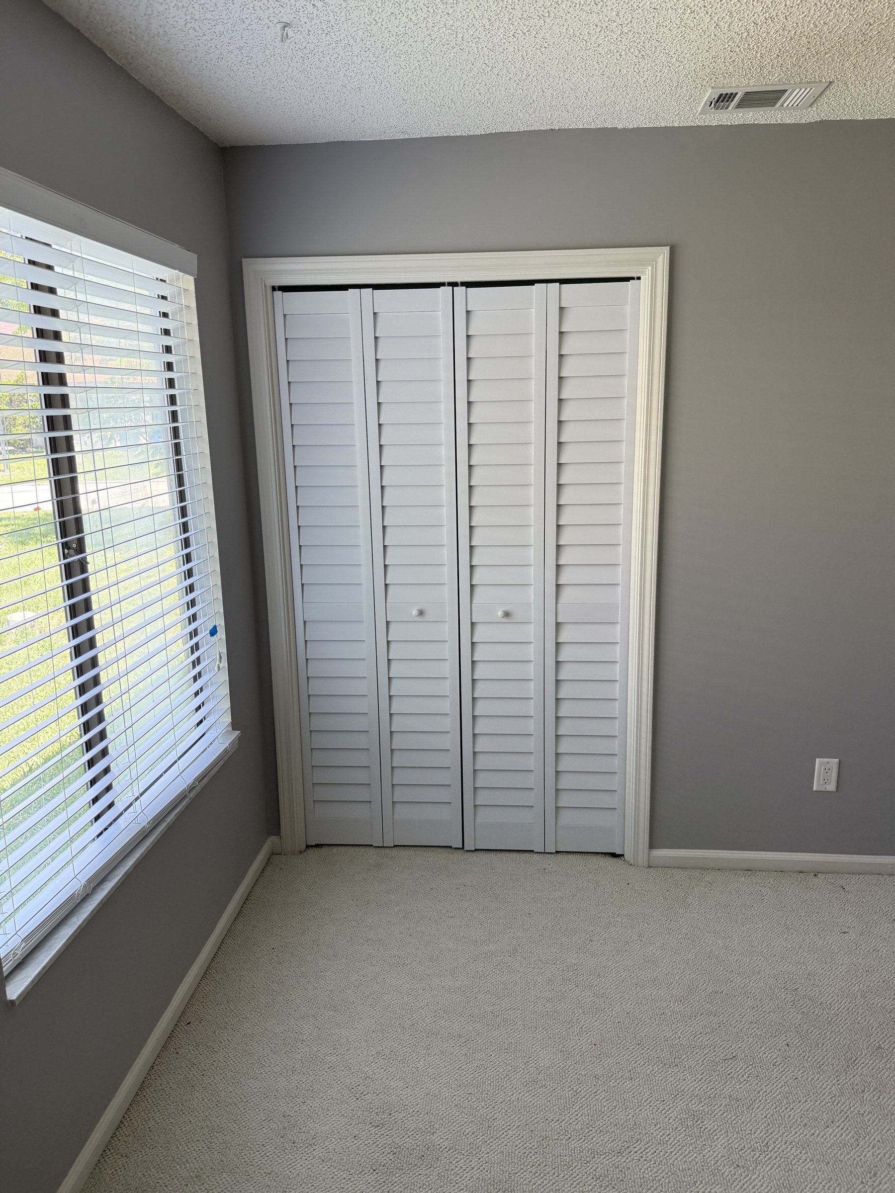 Freshly painted gray bedroom with new white louvered closet doors — drywall and painting by Rent-A Fella