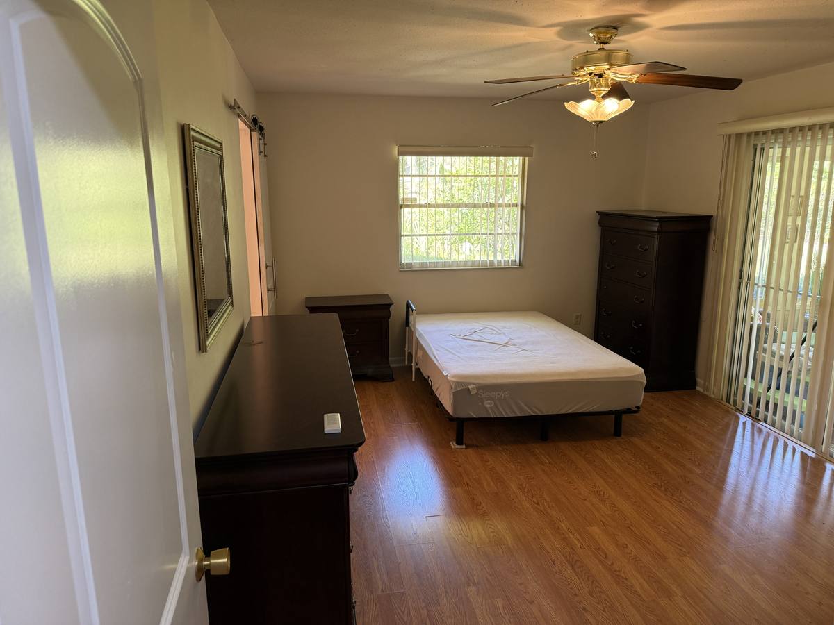Finished bedroom with new hardwood floors, assembled bed frame, dresser, and nightstand