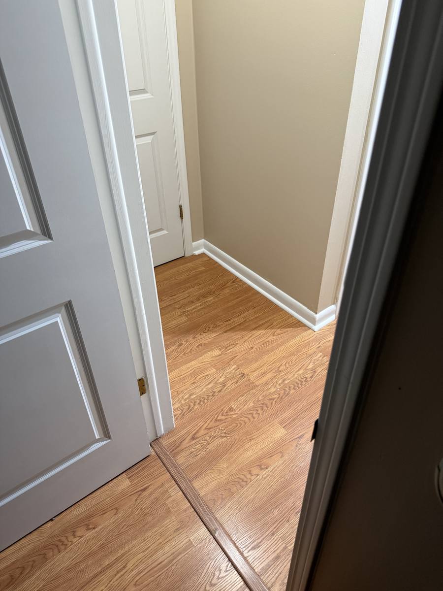 Hallway after paint and trim repair — fresh white baseboards, painted walls and doors, clean finish