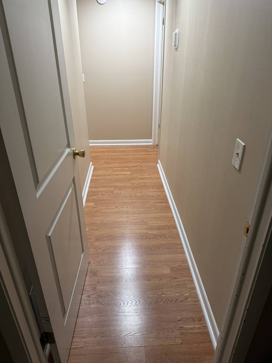 Hallway full corridor view after paint and trim repair — crisp white trim, fresh paint, doors refinished throughout