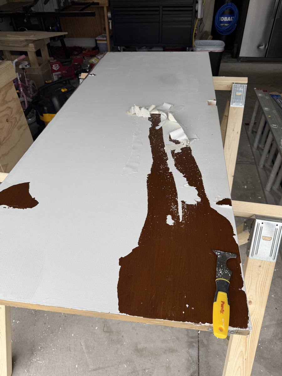 Pocket door panel being stripped and refinished in garage — old finish scraped off